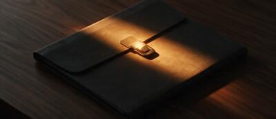 A sealed document folder in a single shaft of amber light — a website RFP that agencies can price — Dsignr Digital